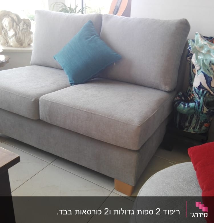 ספה אפורה עם כרית כחולה על רגלי עץ